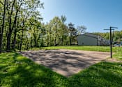 Thumbnail 10 of 20 - A paved area surrounded by trees and a building in the background.