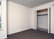 Thumbnail 8 of 15 - A room with a white wall and a brown carpet.