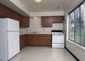 Thumbnail 1 of 15 - A kitchen with white appliances and brown cabinets.