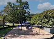 Thumbnail 18 of 21 - A playground with a blue slide and a brown surface.