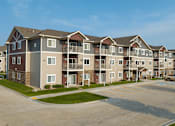 Thumbnail 25 of 29 - Apartment complex with a mix of beige, brown, and tan colored buildings.