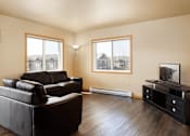 Thumbnail 8 of 29 - A living room with black leather couches and a wooden floor.
