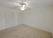 Thumbnail 8 of 20 - A room with a ceiling fan and carpeted floor.