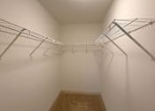 Thumbnail 7 of 20 - Empty walk-in closet with shelving and carpeted floor.