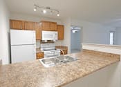 Thumbnail 1 of 20 - A kitchen with granite countertops and white appliances.