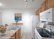 Thumbnail 11 of 20 - A kitchen with a white fridge, white oven, and a painting on the wall.