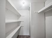 Thumbnail 11 of 23 - a walk in closet in a home with white walls and shelves
