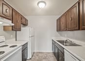 Thumbnail 4 of 23 - a kitchen with white appliances and wooden cabinets