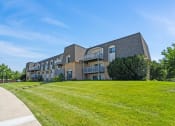 Thumbnail 10 of 33 - a large brick apartment building with a green lawn