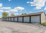 Thumbnail 6 of 8 - A long building with a grey roof and white garage doors.