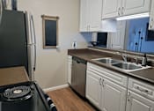 Thumbnail 2 of 8 - A kitchen with white cabinets and a black refrigerator.