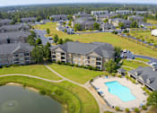 Thumbnail 31 of 33 - A bird's eye view of a residential area with houses, a swimming pool, and a pond.