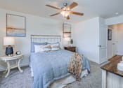 Thumbnail 5 of 33 - A bedroom with a bed, a fan, and a nightstand.