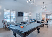 Thumbnail 7 of 33 - A pool table is in the middle of a room with a television and chairs.