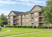 Thumbnail 27 of 33 - A large apartment building with a grassy area in front.