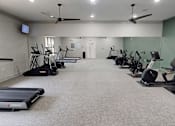 Thumbnail 13 of 33 - A gym with treadmills, exercise bikes, and a television.