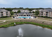 Thumbnail 30 of 33 - A fountain in the middle of a lake in front of apartment buildings.