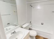 Thumbnail 12 of 23 - A white bathroom with a sink, toilet, and bathtub.
