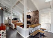 Thumbnail 20 of 23 - A modern open plan living and kitchen area with a brick fireplace.