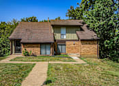 Thumbnail 21 of 23 - A house with a brown roof and a brick exterior is surrounded by greenery.