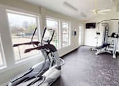 Thumbnail 14 of 23 - A home gym with a treadmill, exercise bike, and weights.