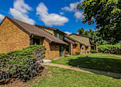 Thumbnail 22 of 23 - A house with a brown roof and a green lawn in front.