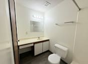 Thumbnail 12 of 16 - A white toilet sits in a bathroom next to a sink and mirror.