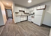 Thumbnail 6 of 16 - A kitchen with white appliances and wooden flooring.