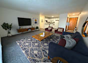 Thumbnail 4 of 16 - A living room with a dark blue couch and a wooden coffee table.