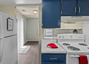 Thumbnail 3 of 27 - open kitchen with blue cabinets and a white stove and refrigerator