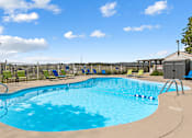 Thumbnail 8 of 11 - A large outdoor swimming pool with sun loungers and a clear blue sky.