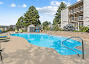 Thumbnail 7 of 11 - A small pool with a slide and a building in the background.