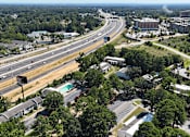 Thumbnail 31 of 31 - A highway with multiple lanes and a green median runs through a city.