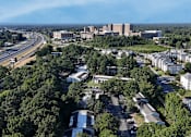 Thumbnail 30 of 31 - A bird's eye view of a highway interchange with buildings and trees in the foreground.