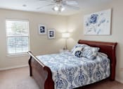 Thumbnail 10 of 35 - A bedroom with a bed, a ceiling fan, and two framed pictures on the wall.