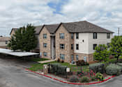 Thumbnail 34 of 35 - A large apartment complex with a parking lot in front.