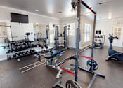 Thumbnail 21 of 35 - A gym with a variety of equipment including weights, a bench press, and a squat rack.