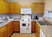 Thumbnail 3 of 35 - A kitchen with a white stove top oven and a white microwave above it.