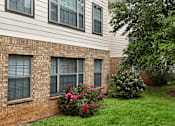 Thumbnail 30 of 35 - A brick wall with windows and flowers in front.