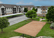 Thumbnail 25 of 35 - A tennis court is surrounded by apartment buildings.