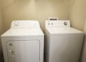 Thumbnail 14 of 35 - Two white front loading washing machines in a laundry room.