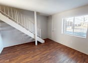 Thumbnail 15 of 26 - A room with a wooden floor and a staircase.
