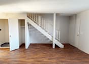 Thumbnail 16 of 26 - A white staircase with a railing is in the middle of a room with wooden floors.