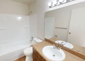 Thumbnail 13 of 26 - A white toilet sits next to a sink in a bathroom.