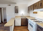 Thumbnail 6 of 26 - A kitchen with a white stove top oven and a white dishwasher.