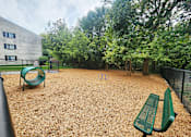 Thumbnail 27 of 36 - A playground with a green slide and two green benches.