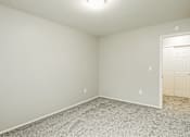 Thumbnail 18 of 31 - A room with a carpeted floor and a door on the right side.