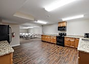 Thumbnail 23 of 31 - A kitchen with wooden floors and a black refrigerator.