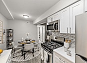 Thumbnail 4 of 31 - A modern kitchen with a dining table and chairs.