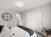 Thumbnail 9 of 31 - A bedroom with a bed, a clock, and a door.